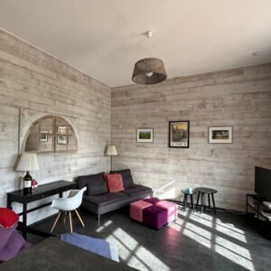 Séjour du gîte de L'Orangerie aménagé avec un canapé, un bureau et des tables basses.