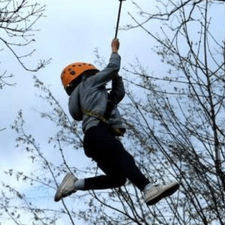 Enfant suspendu au bout d'une corde dans les arbres.