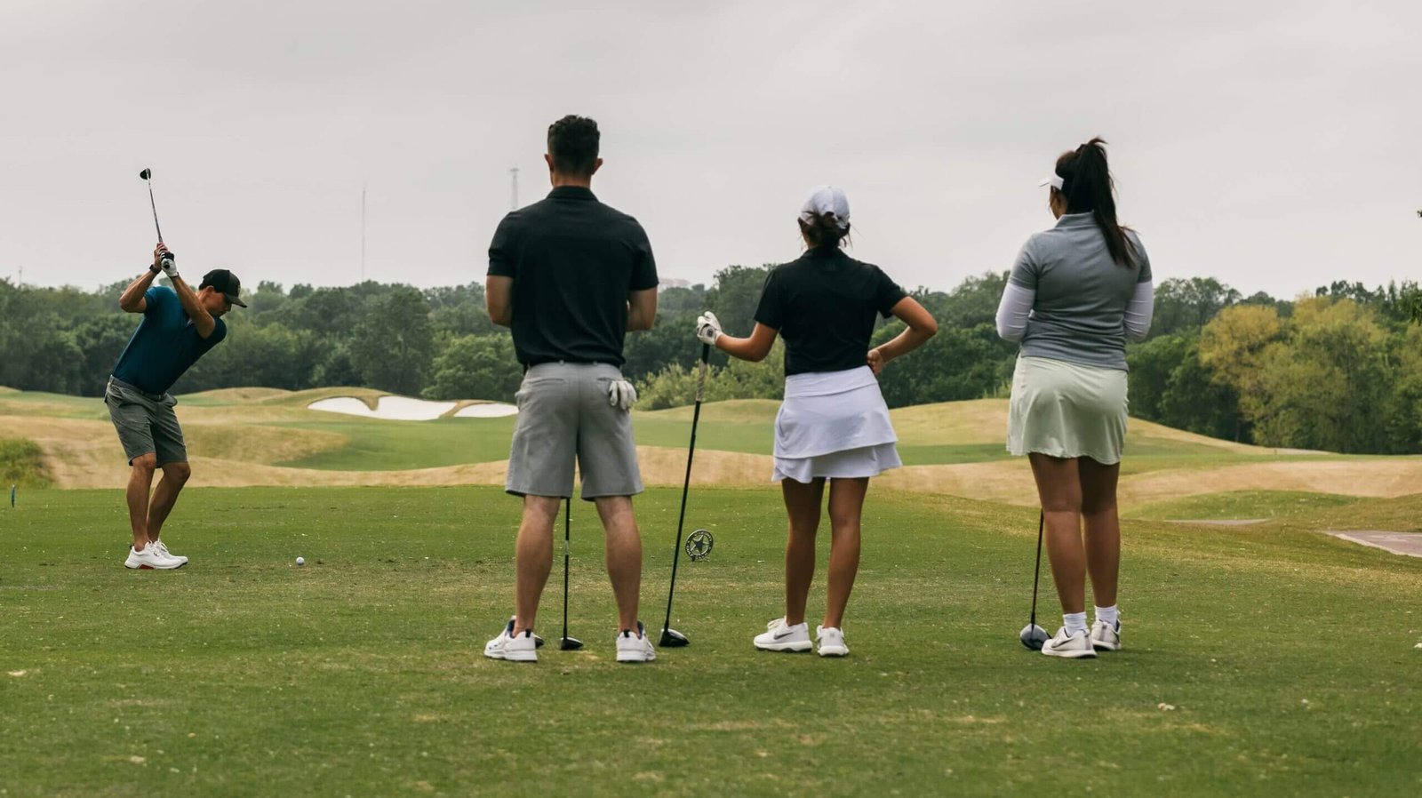 Groupe de golfeurs de dos devant un golf.